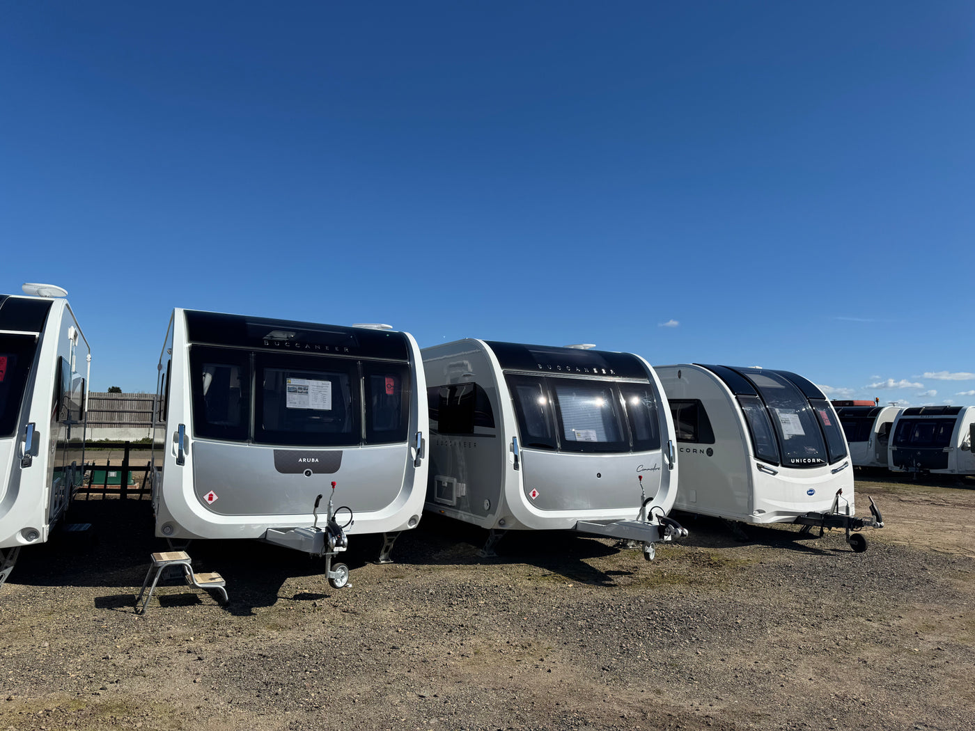Row of silver caravans parked under a clear blue sky
