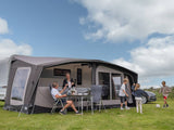 Family enjoying a picnic under a caravan awning on a sunny day.
