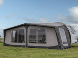 Caravan with an attached awning on a grassy area under a clear sky