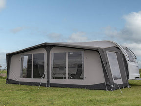 Caravan with an attached awning on a grassy area under a clear sky