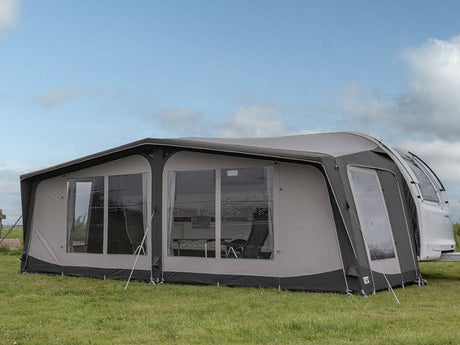 Caravan with an attached awning on a grassy area under a clear sky